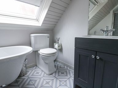 A bathroom with a bathtub toilet and sink cabinet under a skylight window at Kerangarth in Corbridge