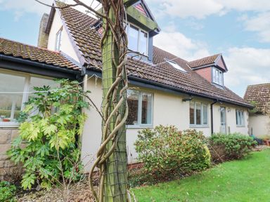The exterior of a house with a tiled roof a garden with shrubs and a wooden post with vines at Kerangarth in Corbridge