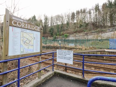 A railway platform with a welcome to Corbridge sign and train directions at Kerangarth in Corbridge