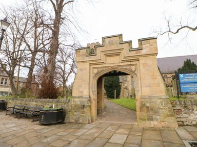 Stone archway entrance with benches and planter on a paved area near churchyard at Kerangarth in Corbridge