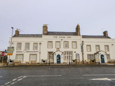 The exterior of The Angel Inn hotel and restaurant with picnic tables outside on a street in Corbridge