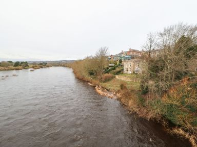 A river flowing beside trees and houses on the riverbank at Kerangarth in Corbridge