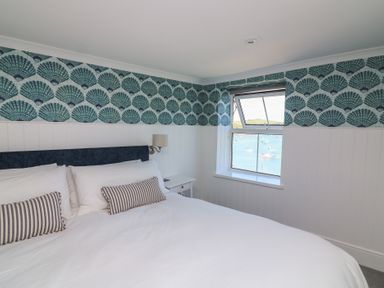 A bedroom with a bed and a window overlooking the water at 43 The Salcombe in Salcombe