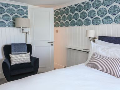 A bedroom with a bed and chair at 43 The Salcombe in Salcombe