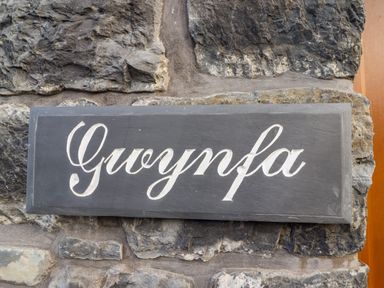 A stone wall with a black sign that reads Gwynfa at Gwynfa in Ysbyty Ifan
