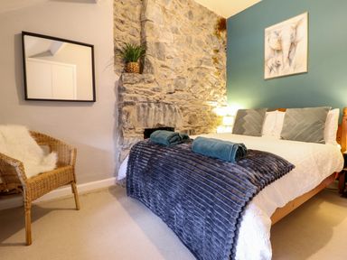 A bedroom with a bed towels on a blanket a chair with a cushion and a mirror on the wall at Gwynfa in Ysbyty Ifan