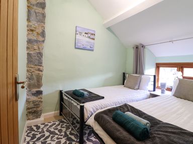 A bedroom with two single beds with folded towels and pillows near a window at Gwynfa in Ysbyty Ifan
