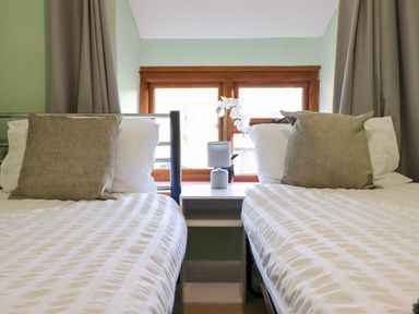 A bedroom with two single beds separated by a white nightstand with a lamp and a flower vase at Gwynfa in Ysbyty Ifan