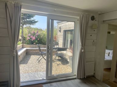 A living room with a view of the garden at The Cow Shed in Mawgan Porth