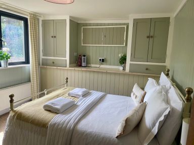A bedroom with a bed and cabinets at The Cow Shed in Mawgan Porth