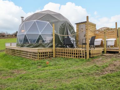 A dome tent on a wooden platform with outdoor chairs and clawfoot bathtubs at Meadow View - Bryn-Mawr Retreat in Brynmawr near Llanymynech