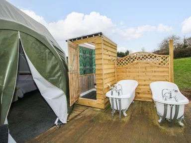 An outdoor area with two bathtubs a wooden shower enclosure and a green tent with an open entrance at Meadow View - Bryn-Mawr Retreat in Brynmawr near Llanymynech
