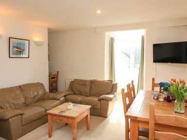 A living room with brown leather sofas a wooden coffee table and a dining table with chairs and flowers at Millers Loft in Modbury