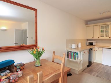 A kitchen and dining area with a wooden table and chairs flowers on the table and kitchen appliances at Millers Loft in Modbury