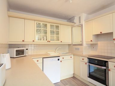 A kitchen with cream cabinets a dishwasher a microwave and an oven at Millers Loft in Modbury