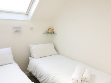 Two single beds with white linens and rolled towels on one bed in a bedroom at Millers Loft in Modbury