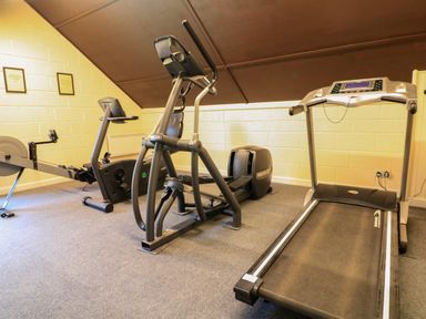 A small gym room with a treadmill elliptical machine and rowing machine at Millers Loft in Modbury