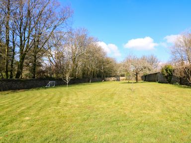 A large grassy garden with small trees a football goal and a stone wall at Millers Loft in Modbury