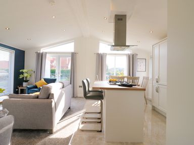 An open living room and kitchen with sofas and bar stools at Number 43 The Poplars in Burnham Market