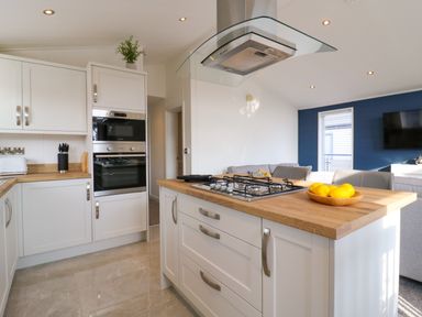 A kitchen with white cabinets wooden countertops a gas stove and a bowl of lemons at Number 43 The Poplars in Burnham Market