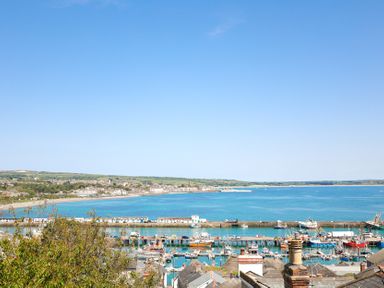 A scenic view of a harbor with boats and hills at Kittiwake Newlyn