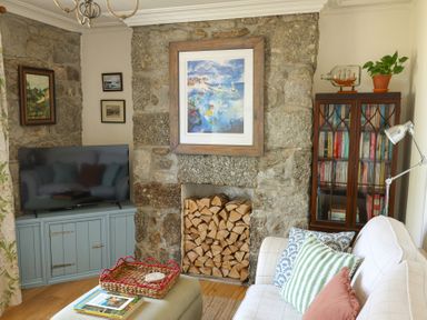 A living room with a television and a stone wall at Kittiwake Newlyn