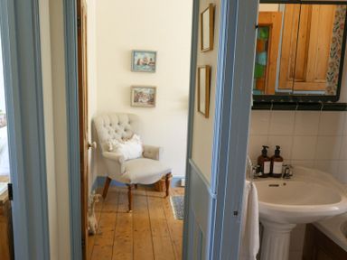 A bathroom with a sink and an armchair at Kittiwake Newlyn