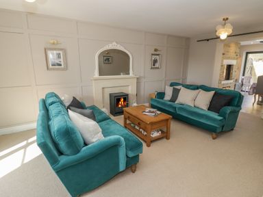 A living room with two teal sofas a wooden coffee table and a fireplace at 2 Summers Way Moreton-In-Marsh