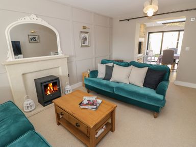 A living room with green sofas a wooden coffee table and a fireplace at 2 Summers Way in Moreton-In-Marsh