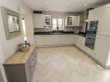 A kitchen with white cabinets black countertops and wood floor at 2 Summers Way in Moreton In Marsh