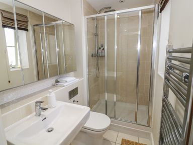 A bathroom with a sink, toilet, shower with glass doors, mirrored cabinet, and towel warmer at 2 Summers Way in Moreton-In-Marsh