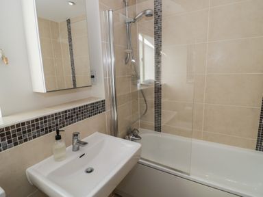 A bathroom with a sink and a bathtub with a showerhead at 2 Summers Way in Moreton-In-Marsh