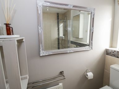 A bathroom with a large ornate mirror reflecting a tiled shower area and a cabinet at 2 Summers Way in Moreton-In-Marsh