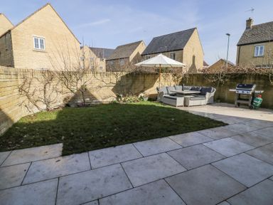 A backyard with grass area patio furniture with umbrella and a grill at 2 Summers Way in Moreton-In-Marsh