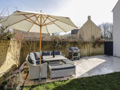 An outdoor patio with a table umbrella seating and barbecue grill at 2 Summers Way in Moreton-In-Marsh