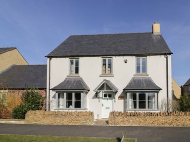 A detached house with a peaked roof and two bay windows behind a stone wall at 2 Summers Way in Moreton-In-Marsh
