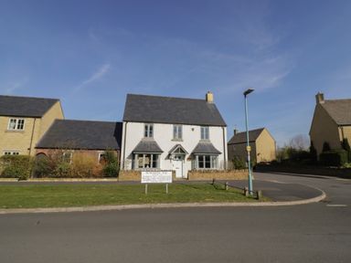 A residential street with houses a white house with a triangular porch and slate roofs near a streetlamp at 2 Summers Way Moreton-In-Marsh