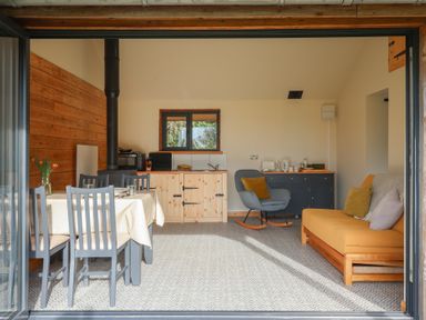 A dining area with a table and four chairs a kitchenette with wood cabinets a rocking chair and a sofa at Beech Tree Cabin Goodmanham near Market Weighton