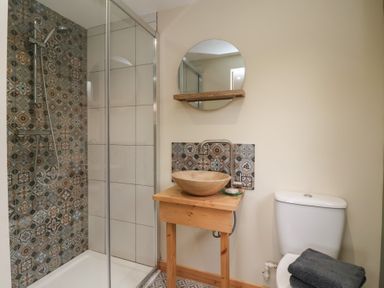 A bathroom with a shower enclosure a wooden sink stand with a round basin and a toilet with folded towels at Beech Tree Cabin in Goodmanham near Market Weighton