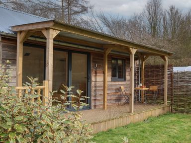 A wooden porch with a table and two chairs outside a cabin at Beech Tree Cabin in Goodmanham near Market Weighton