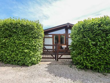An outdoor view of a property with a gate and shrubs at Newton Calm in Newton Ferrers