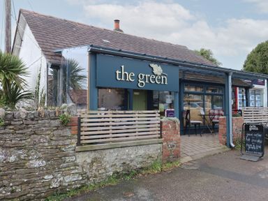 The exterior of a cafe named the green with outdoor seating and a chalkboard sign on the pavement at Skyview in Newton Ferrers