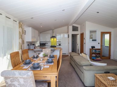 An open plan living and dining area with a table and kitchen at Skyview in Newton Ferrers