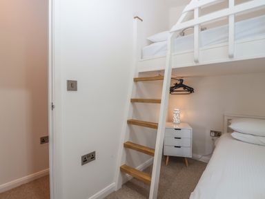 A bedroom with a bunk bed and nightstand at Skyview in Newton Ferrers
