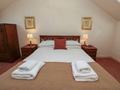 A bedroom with a double bed two bedside tables with lamps and a wardrobe at Aubretia Trail in Akeld near Wooler