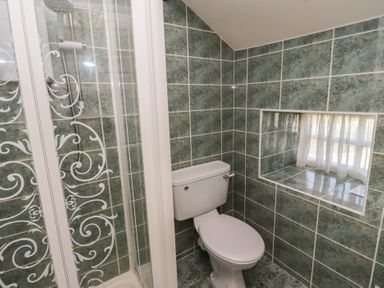 A bathroom with a toilet and a shower with a glass door at Aubretia Trail Akeld near Wooler