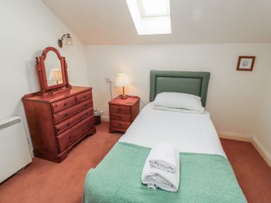 A bedroom with a single bed a dresser with mirror a bedside table and a skylight at Aubretia Trail in Akeld near Wooler