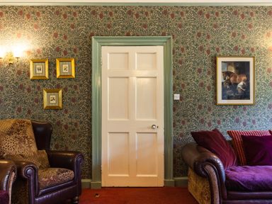 A living room with a door and framed paintings at Cheviot Manor Akeld near Wooler