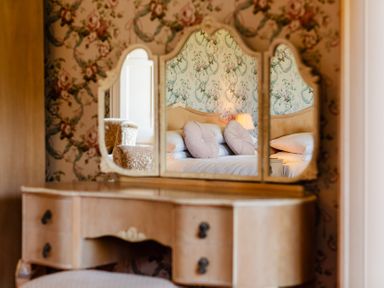 A dressing table with a mirror reflecting a bed at Cheviot Manor in Akeld near Wooler