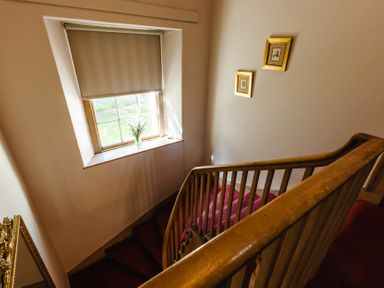 A staircase with a window and framed pictures at Cheviot Manor in Akeld near Wooler